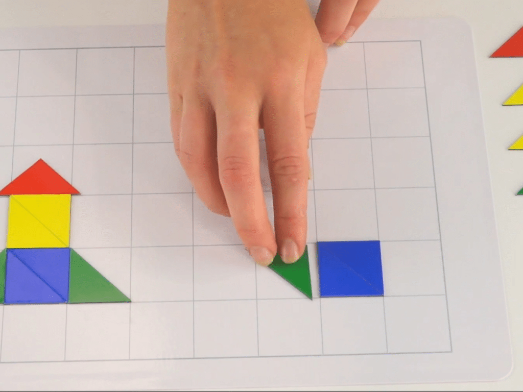 A hand is moving shapes on a grid, solving a shape challenge