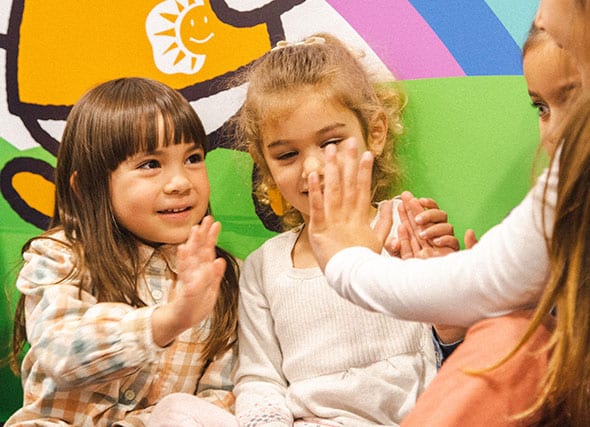 Raising EQ and IQ for kids using holistic learning program, featuring preschool aged girls in a Shichida centre. They are chatting, laughing and high-fiving each other.