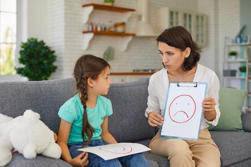 An adult showing a child a drawing of a sad face