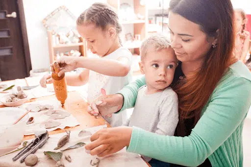 Parent involvement for successful early learning - a mum and kids playing with nature items.