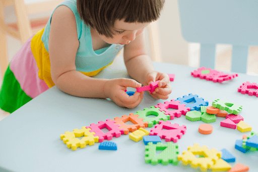 Young girl playing with a foam shape puzzle