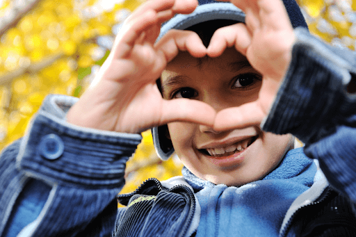 Happy child showing love heart with his hands