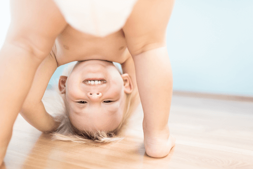 Young child in a diaper playing happily, showing a big smile