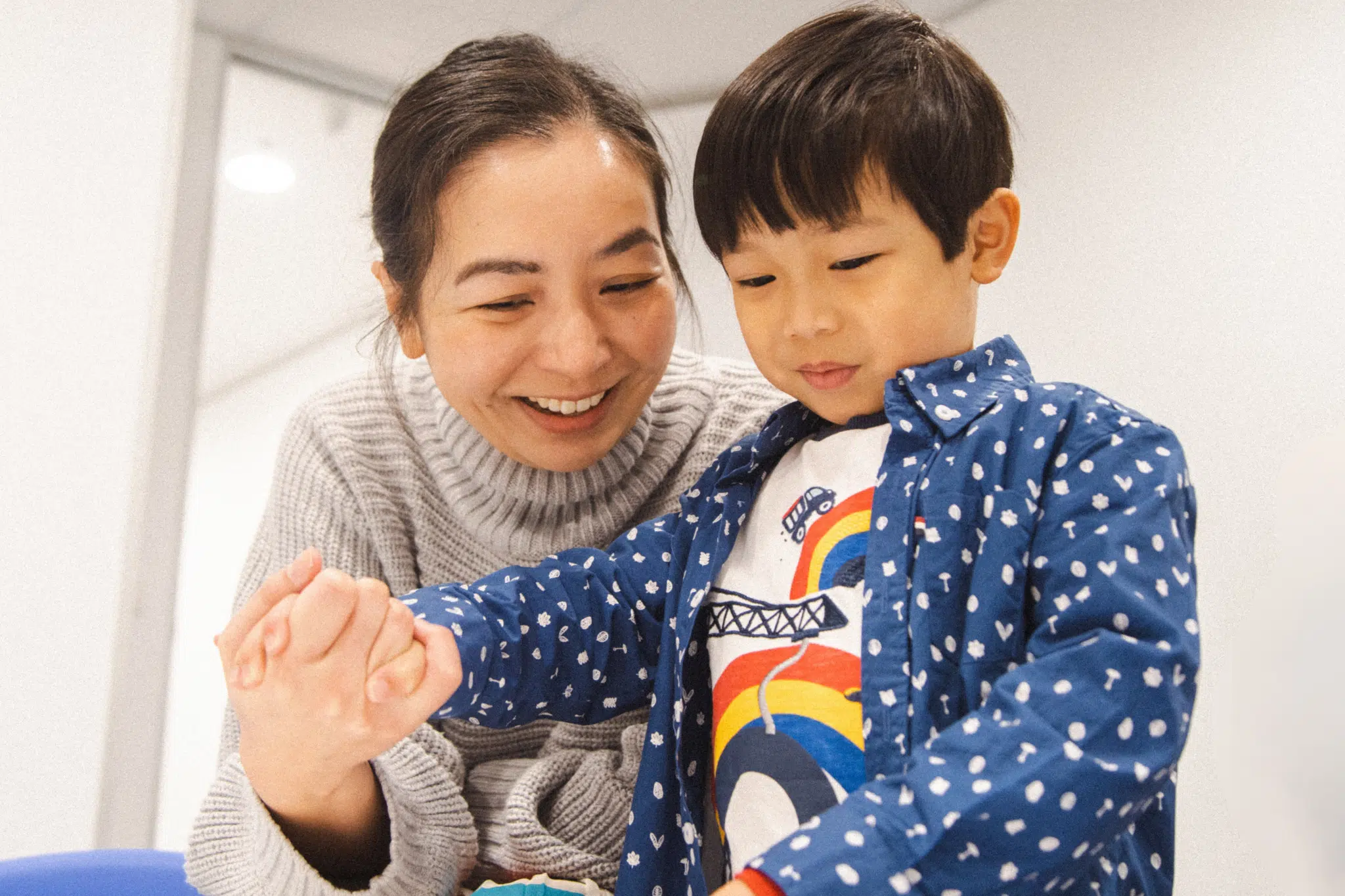 Happy mum holding her young son's hand in a Shichida class