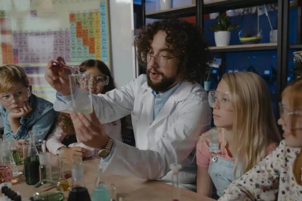 Science literacy as presented by a science teacher doing an experiment with kids in class observing him