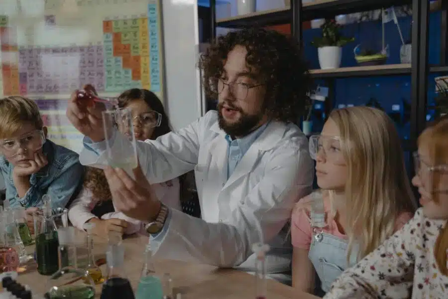 Science literacy as presented by a science teacher doing an experiment with kids in class observing him