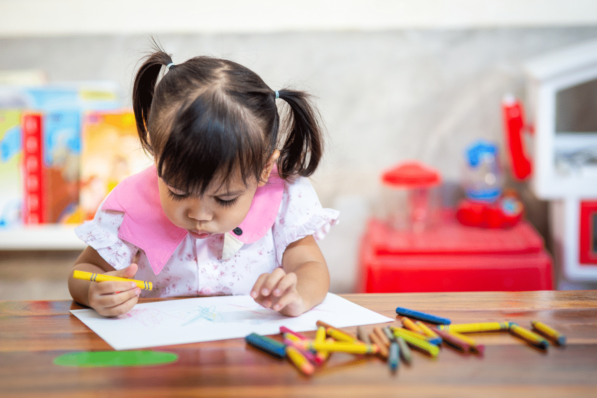 A little girl colouring with crayons