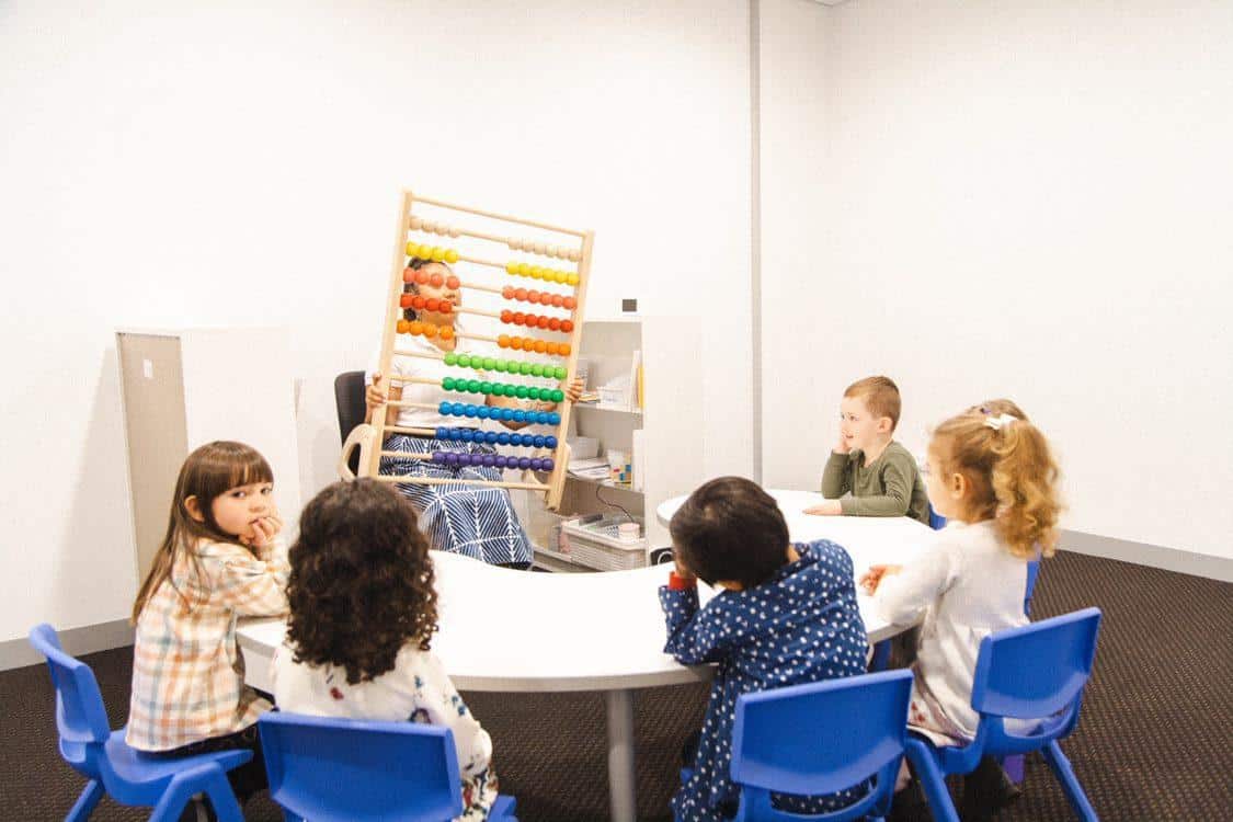 A Shichida teacher holds a large colourful abacus to guide kids in the class through step counting