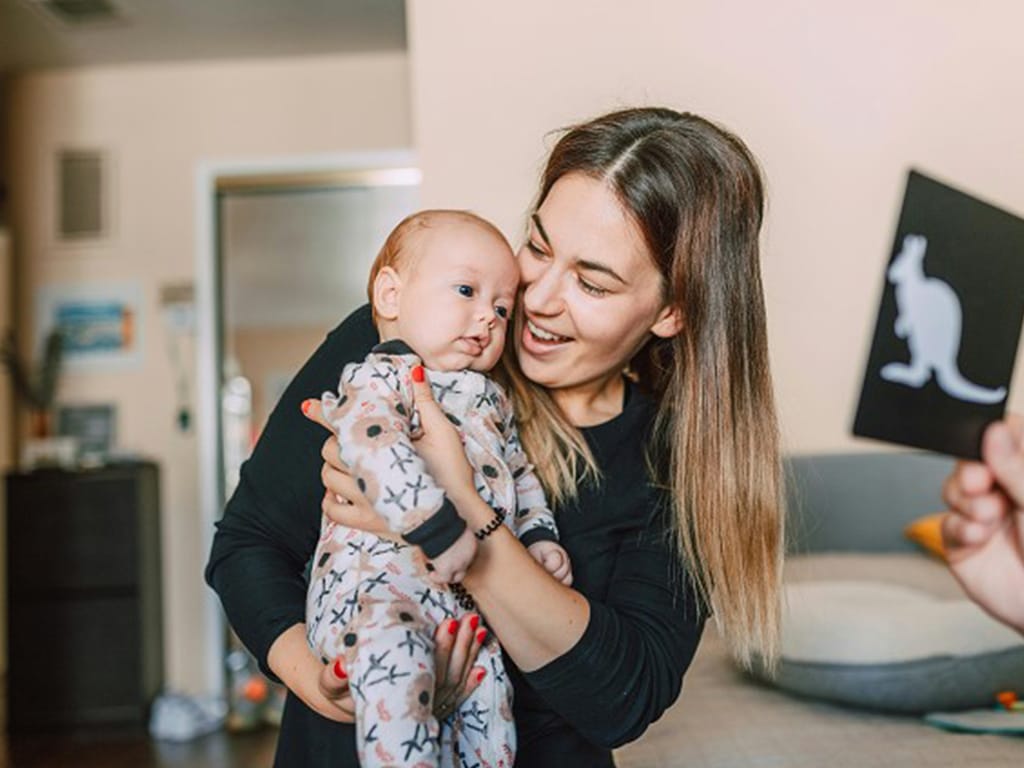 A mum holding her baby, showing the baby high contrast flashcards for brain development