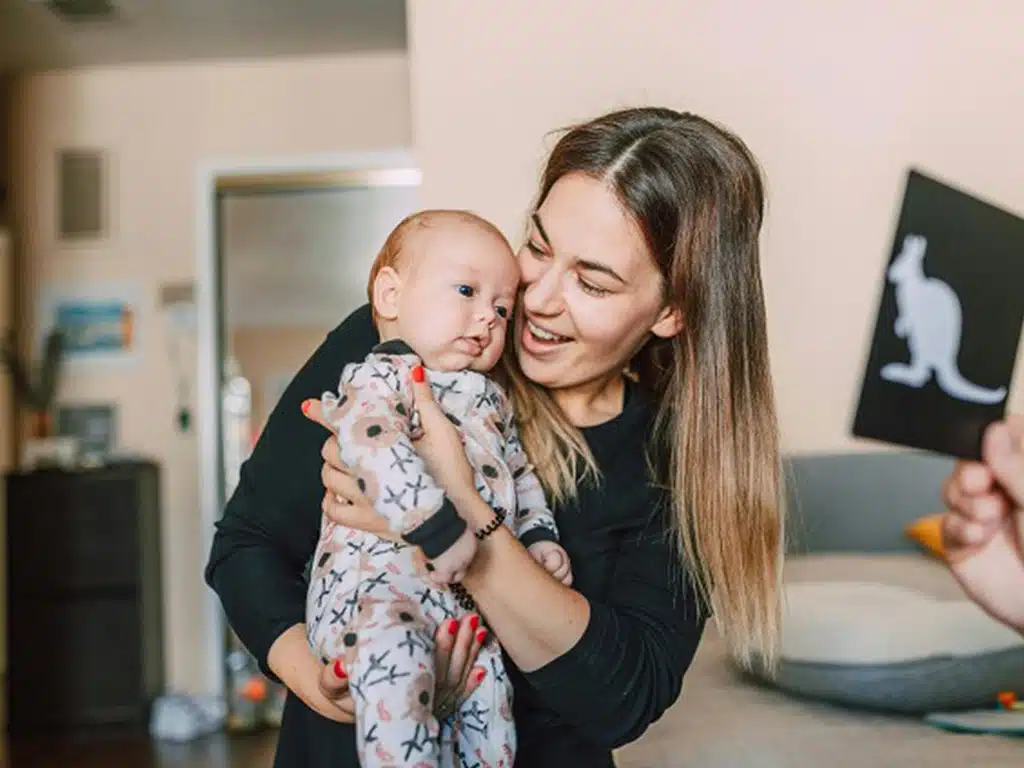 A mum holding her baby, showing the baby high contrast flashcards for brain development