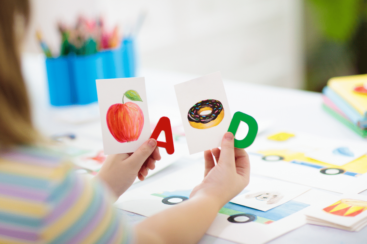 A preschool child holding Alphabet letters and cards as a memory matching activity