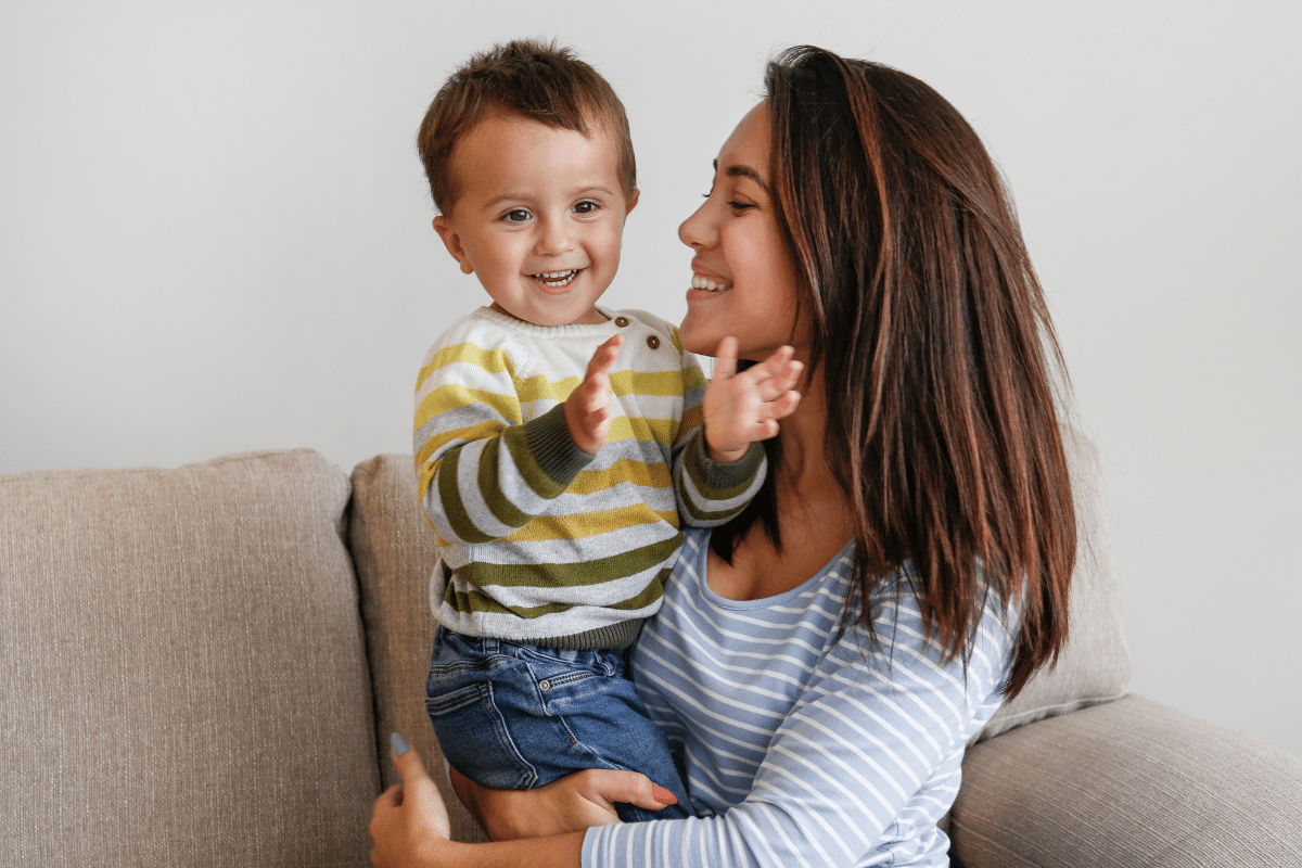 A mother holding a young toddler looking happy for The Power of Positivity