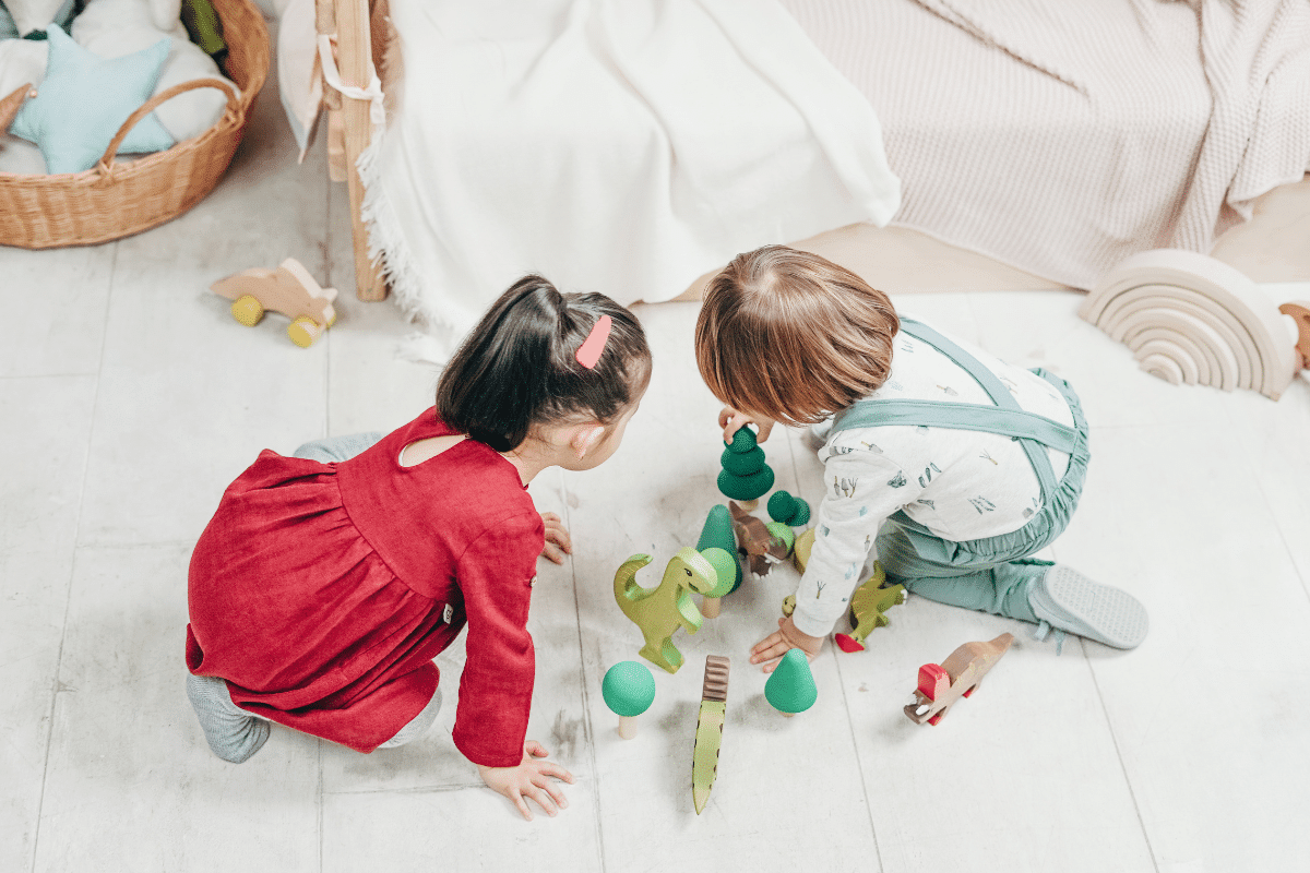 Two kids playing with toys on a white floor as a demonstration of Long Term vs Short Term Memory development in kids