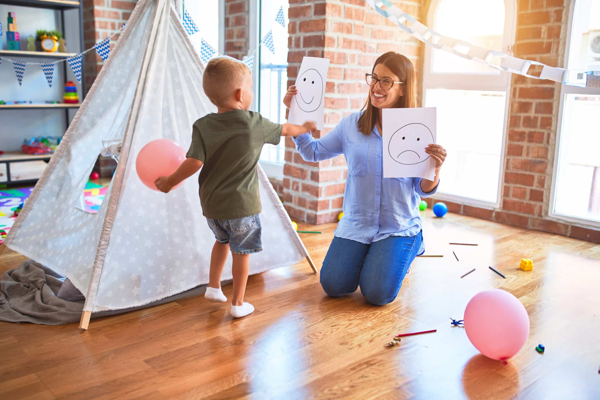 Young therapist woman speaking with child, counselor and behaviour correction at the office around toys, teaching to identify emotions