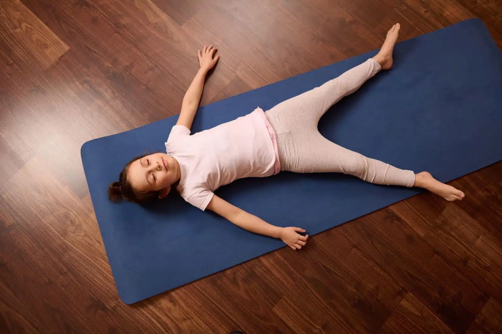 A young girl relaxing on a yoga mat showing the benefit of mindfulness activities for children