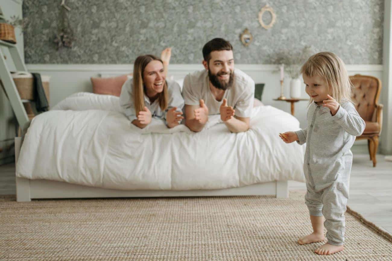 Intrinsic motivation in children, featuring a Couple Lying on the Bed while Looking at Their Young Daughter Standing