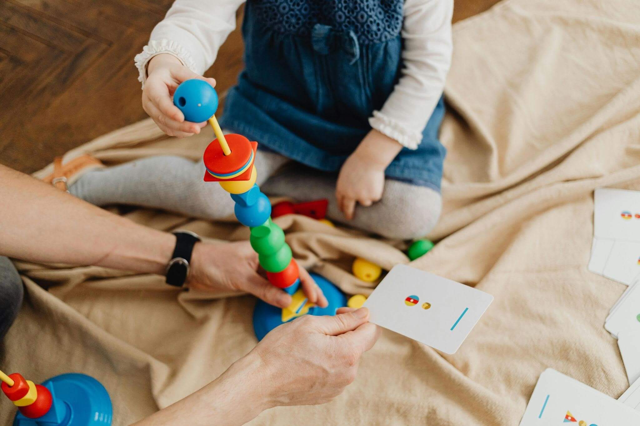 Child playing with an educational toy, matching colourful shapes to pattern cards.