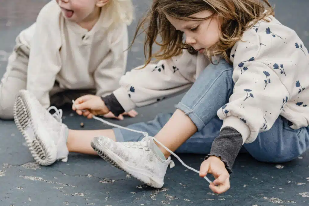 Developing fine motor skills through everyday fine motor activities, here a preschooler is tying her shoelaces.