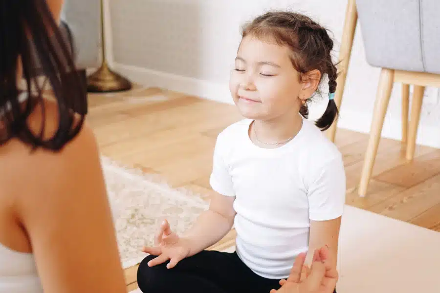Kids mental health, here a preschooler is doing meditation with her mum at home.