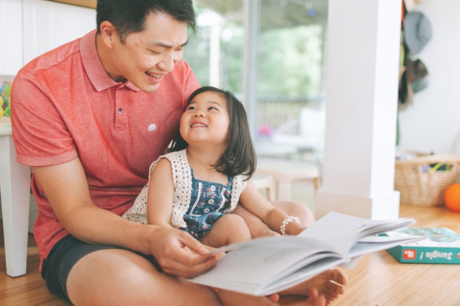 Build children's confidence through reading together, here a dad is reading with his toddler.