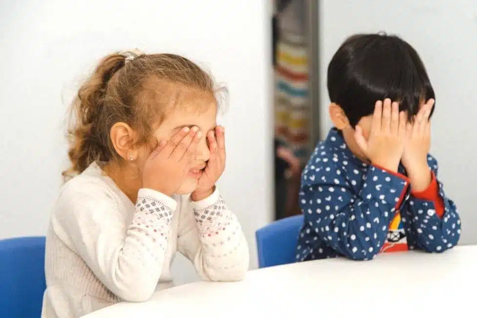 a boy and girl covering their eyes with their hands as they practise visualisation during a Shichida class