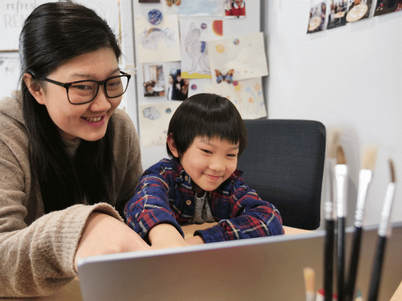 A woman and a child are engaged in looking at a laptop screen together, sharing a moment of curiosity and learning