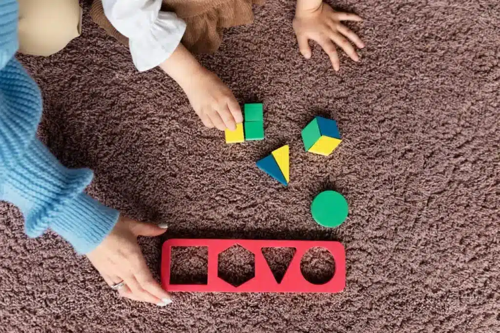 Sensory ideas for infants - A woman and child joyfully playing with colorful blocks on a soft carpet in a bright, inviting room