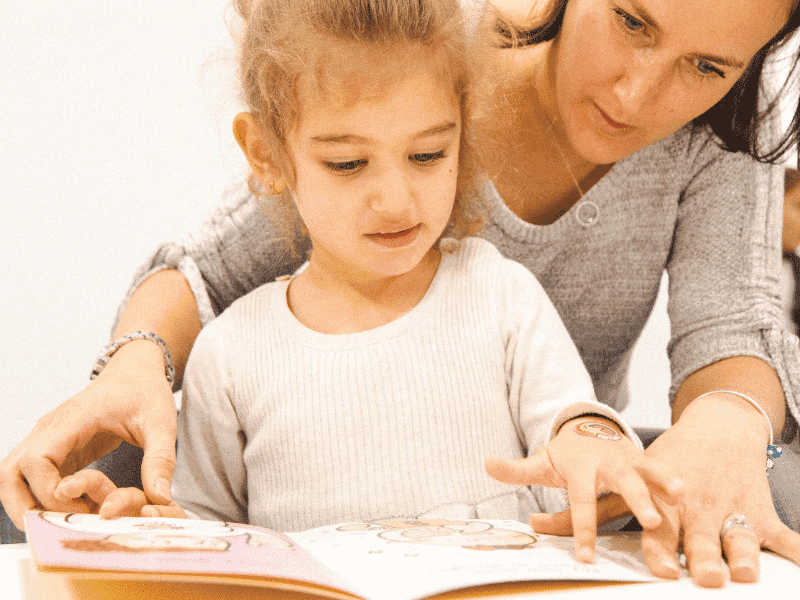 Mother teaching daughter with a Book during a Shichida class