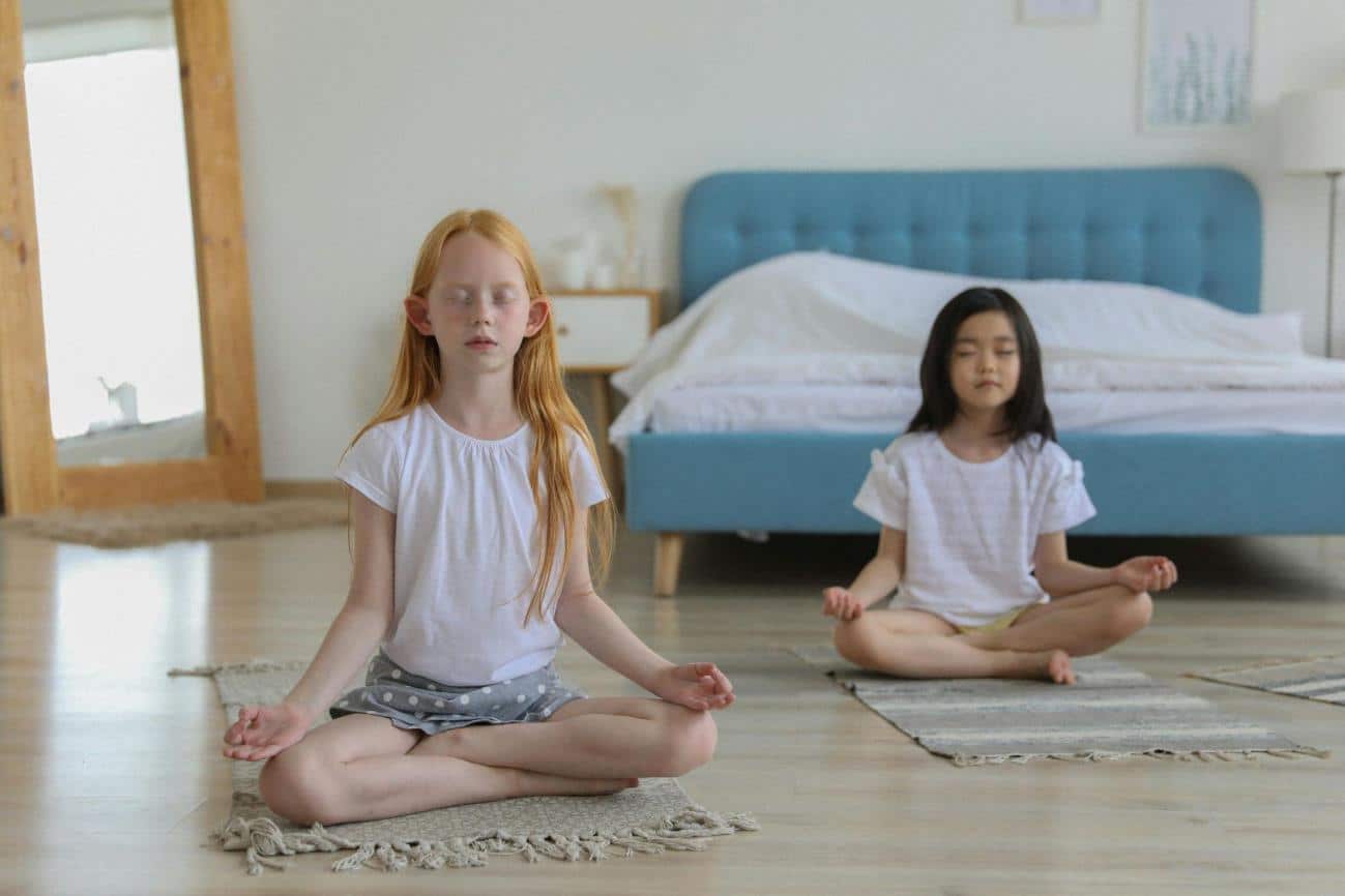 Girls with reddish and black hair meditating in room