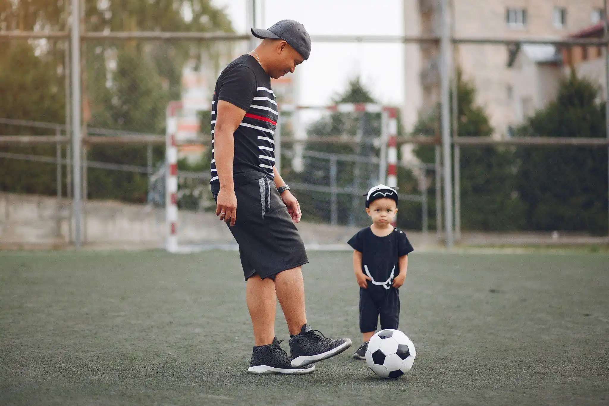 A toddler and his dad playing with a ball.