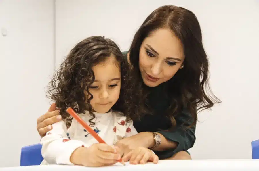 Image by Shichida Australia: A mum sitting beside her child as she traces letters, providing gentle guidance while building letter formation, pencil control and writing confidence.
