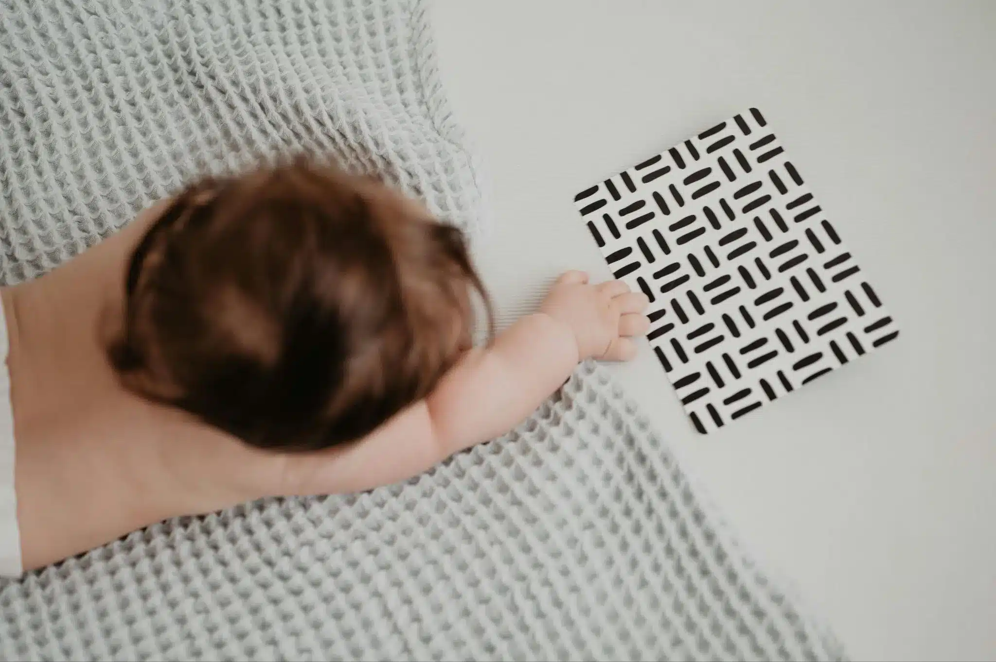 Baby focusing on high-contrast visual cards during an awake play session.