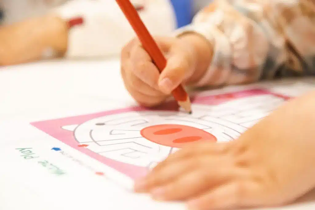 Child carefully drawing through a maze puzzle with a pencil