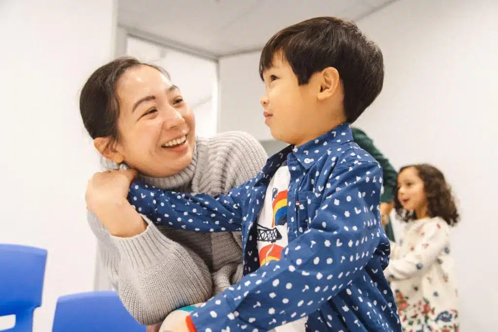 A smiling adult and a young boy laughing together during a Shichida early learning class